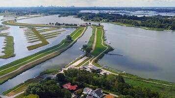An aerial view of a riverside area with a lock system, a bridge, and a city skyline in the distance.