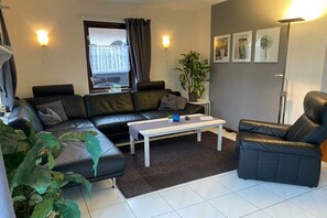 Relax in this stylish living room with a black leather sofa, armchair, and a beautiful potted plant.
