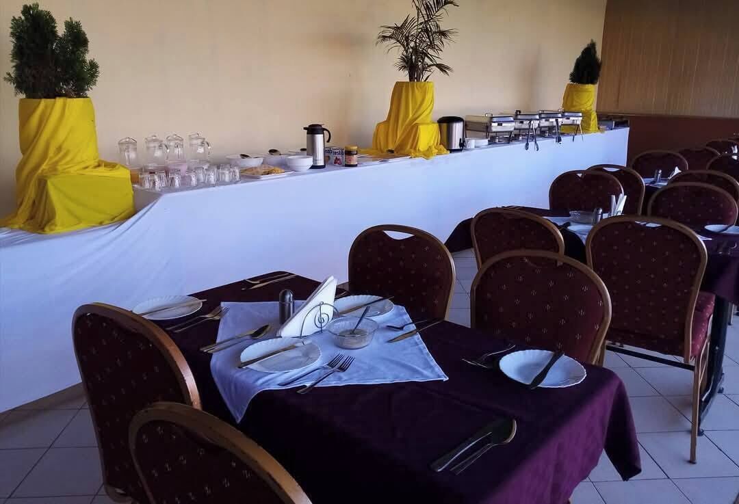 Un salón de conferencias con mesas dispuestas para una reunión, equipado con tarjetas de identificación, platos, cubiertos y una estación de café.