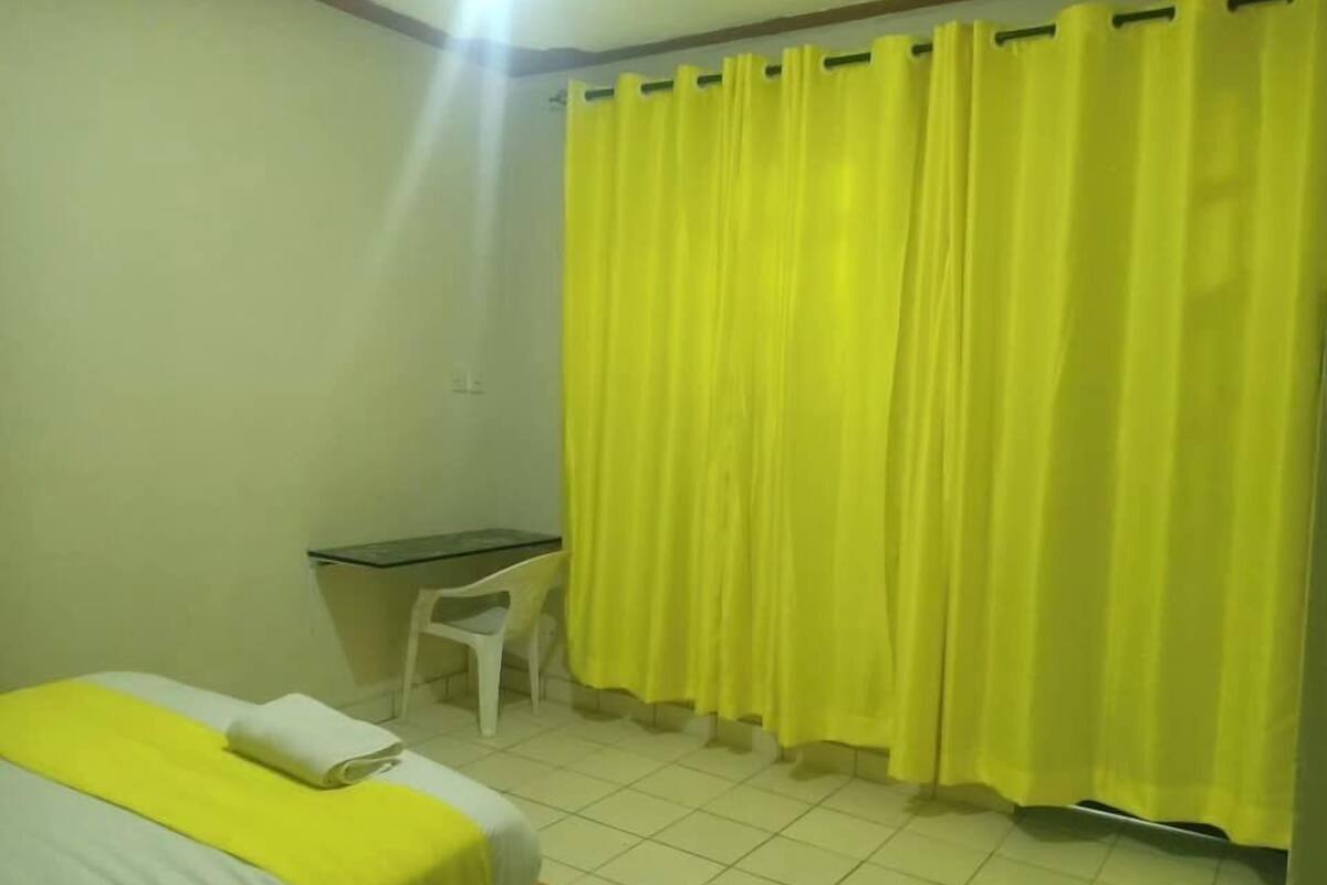 Una habitación pequeña y sencilla con una cama, un escritorio y una silla.