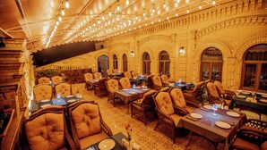 Un restaurante con varias mesas y sillas, luces colgantes y fachada de ladrillo.
