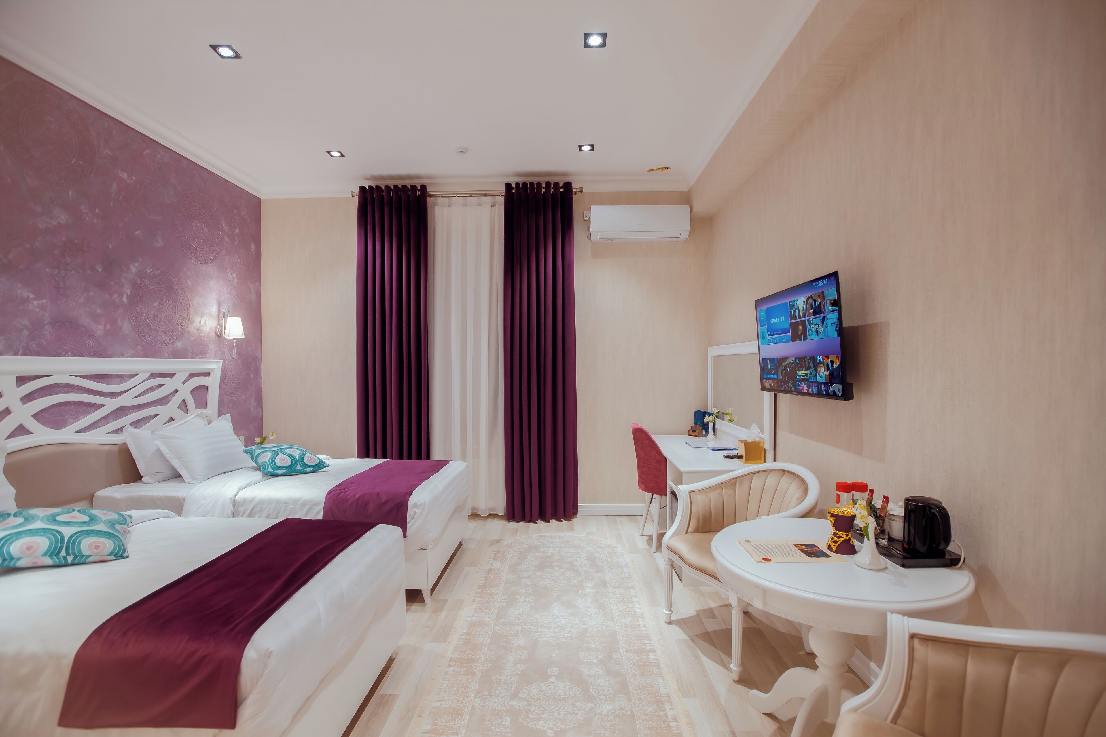 Habitación de hotel con dos camas, un escritorio, una silla y un televisor.