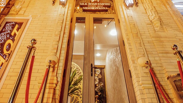 Una entrada imponente con un toldo, banderas y un letrero que dice "Silk Road Empire Mehmona".
