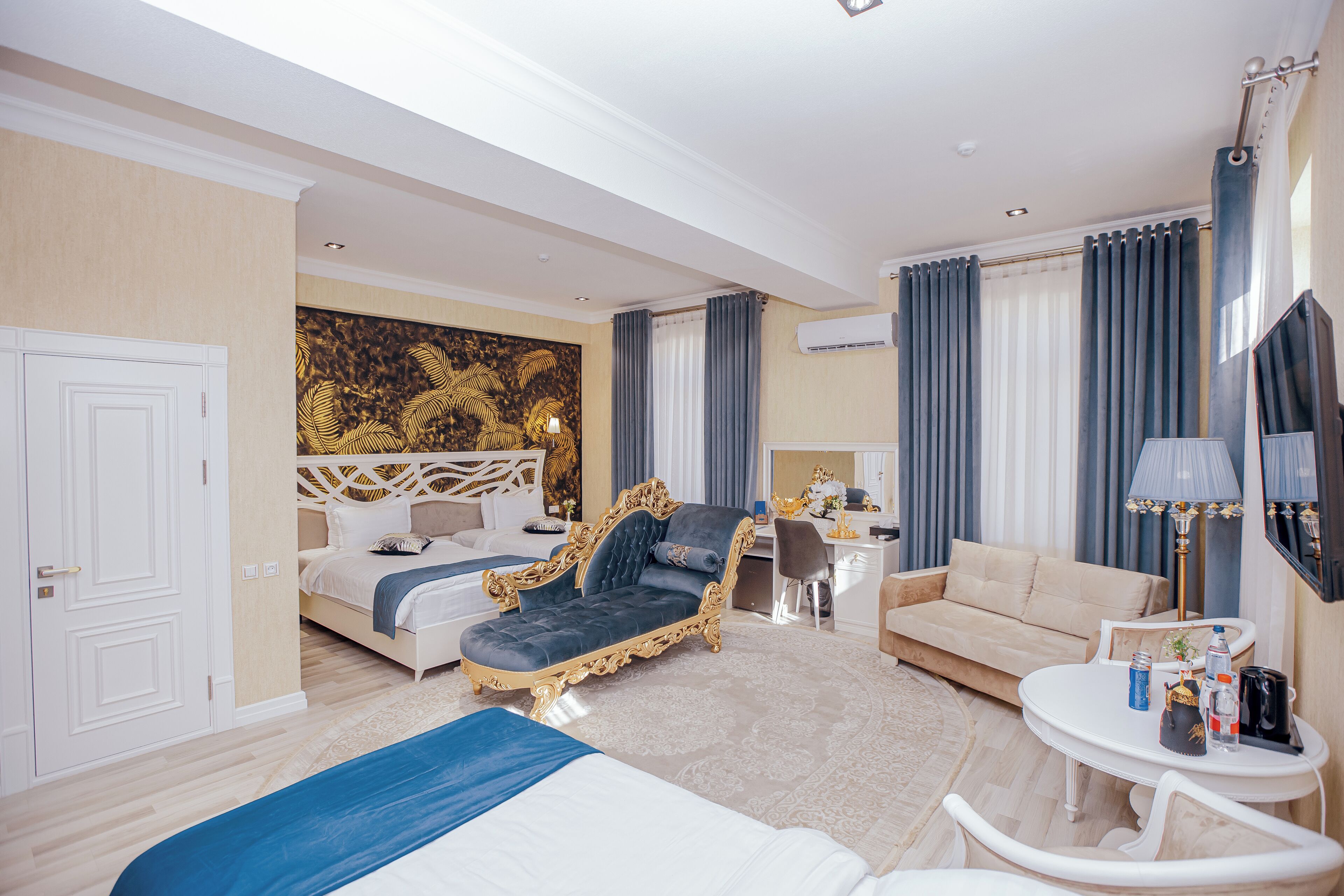 A hotel room with a king-sized bed, a sofa, a desk, and a TV.