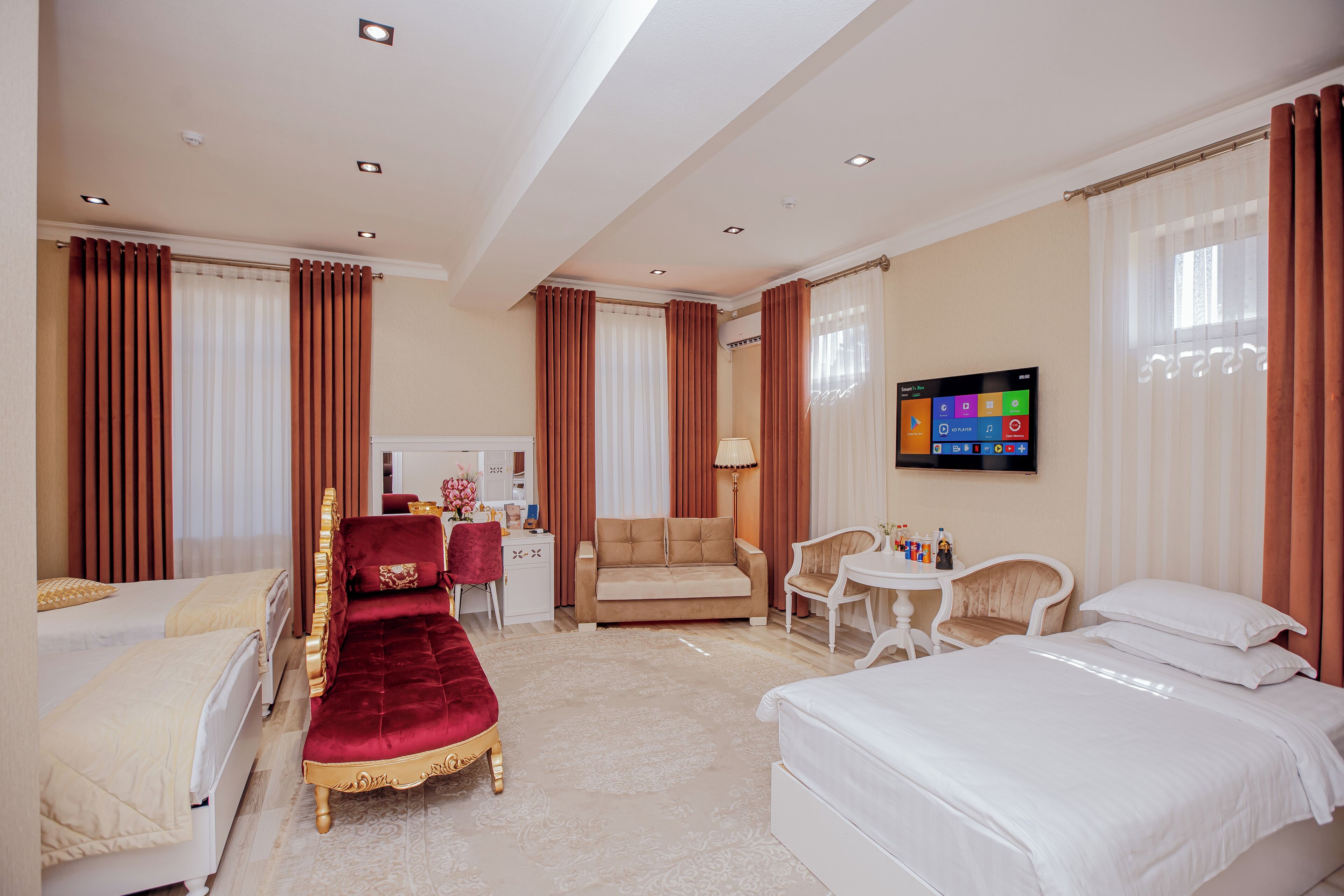 Una habitación de hotel con dos camas, un sofá, un televisor y un escritorio con una silla.