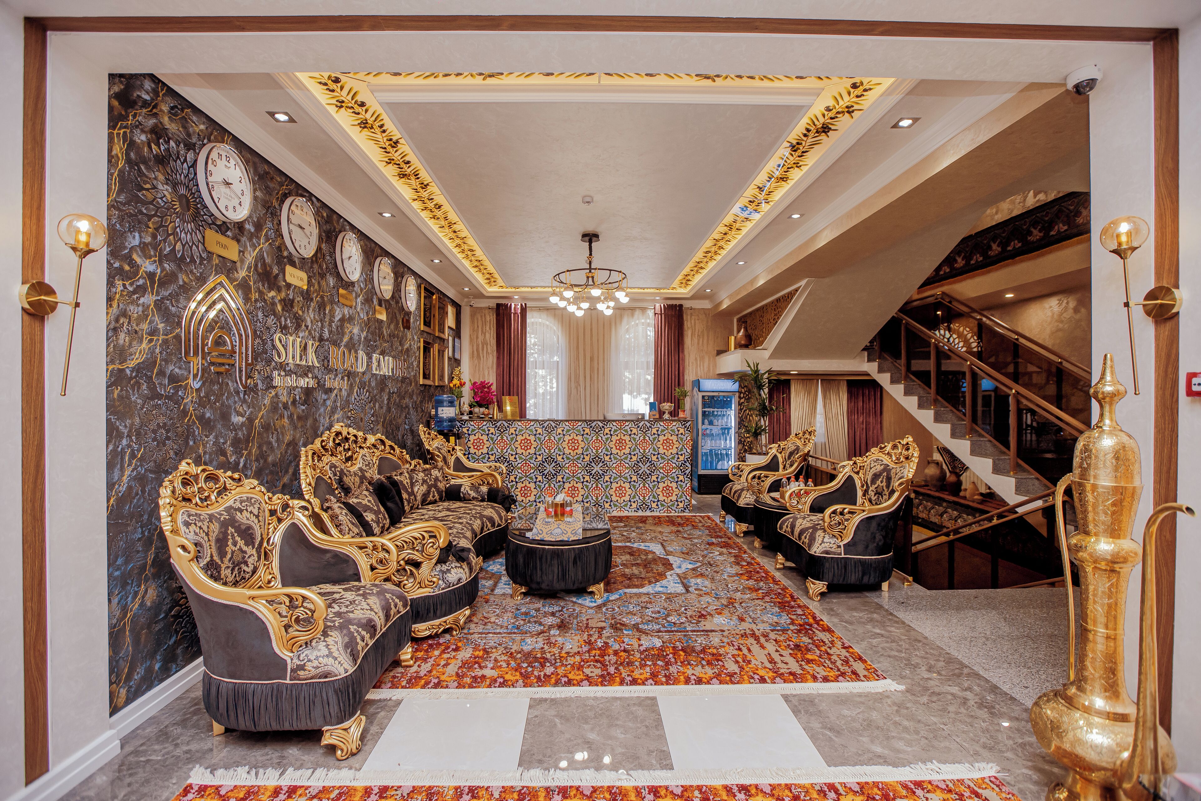 A luxurious lobby with ornate sofas, a patterned carpet, and a grand staircase.