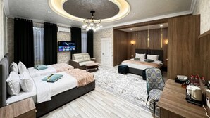 Una habitación de hotel moderna con una cama grande, una cama más pequeña, un sofá, un escritorio y un televisor.