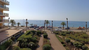 A coastal hotel with a view of the sea, a parking area, and a landscaped garden.