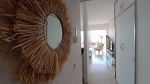 A hallway with a large mirror and a door leading to a room.