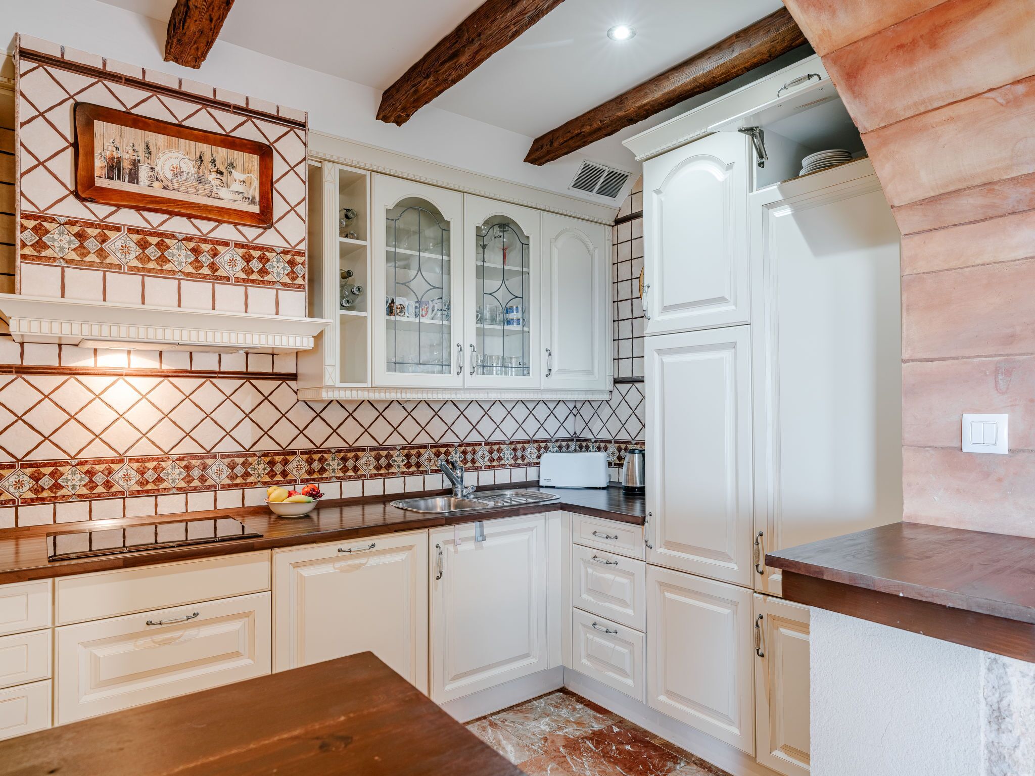 A kitchen with white cabinets, a wooden countertop, and a tiled backsplash.
