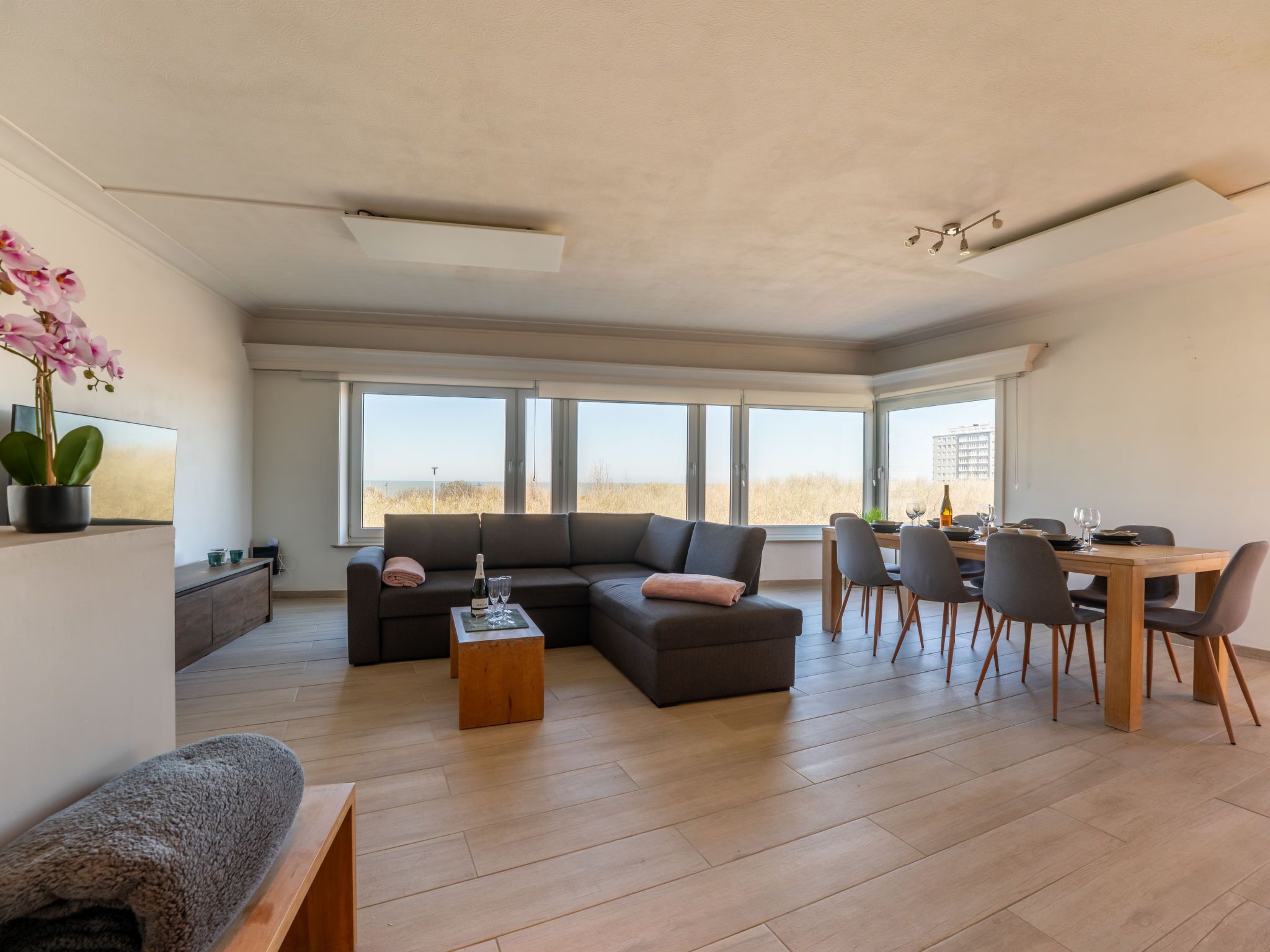A spacious living area with a large sectional sofa, a wooden coffee table, and a dining table set for six.