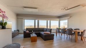 A spacious living area with a large sectional sofa, a wooden coffee table, and a dining table set for six.
