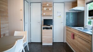 Een moderne keuken met een ingebouwde televisie, houten kastjes en een eethoek met witte stoelen.
