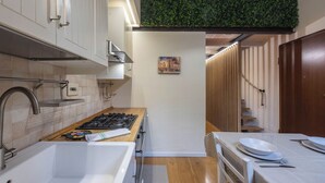 A modern kitchen with white cabinets, a gas stove, a sink, and a wooden countertop.