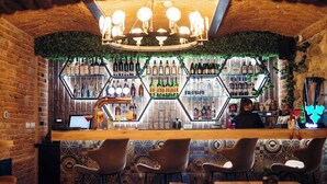 A bar area with hexagonal shelves of bottles, a wooden counter, and bar stools. - Hotel Bucheland (Gura Humorului)