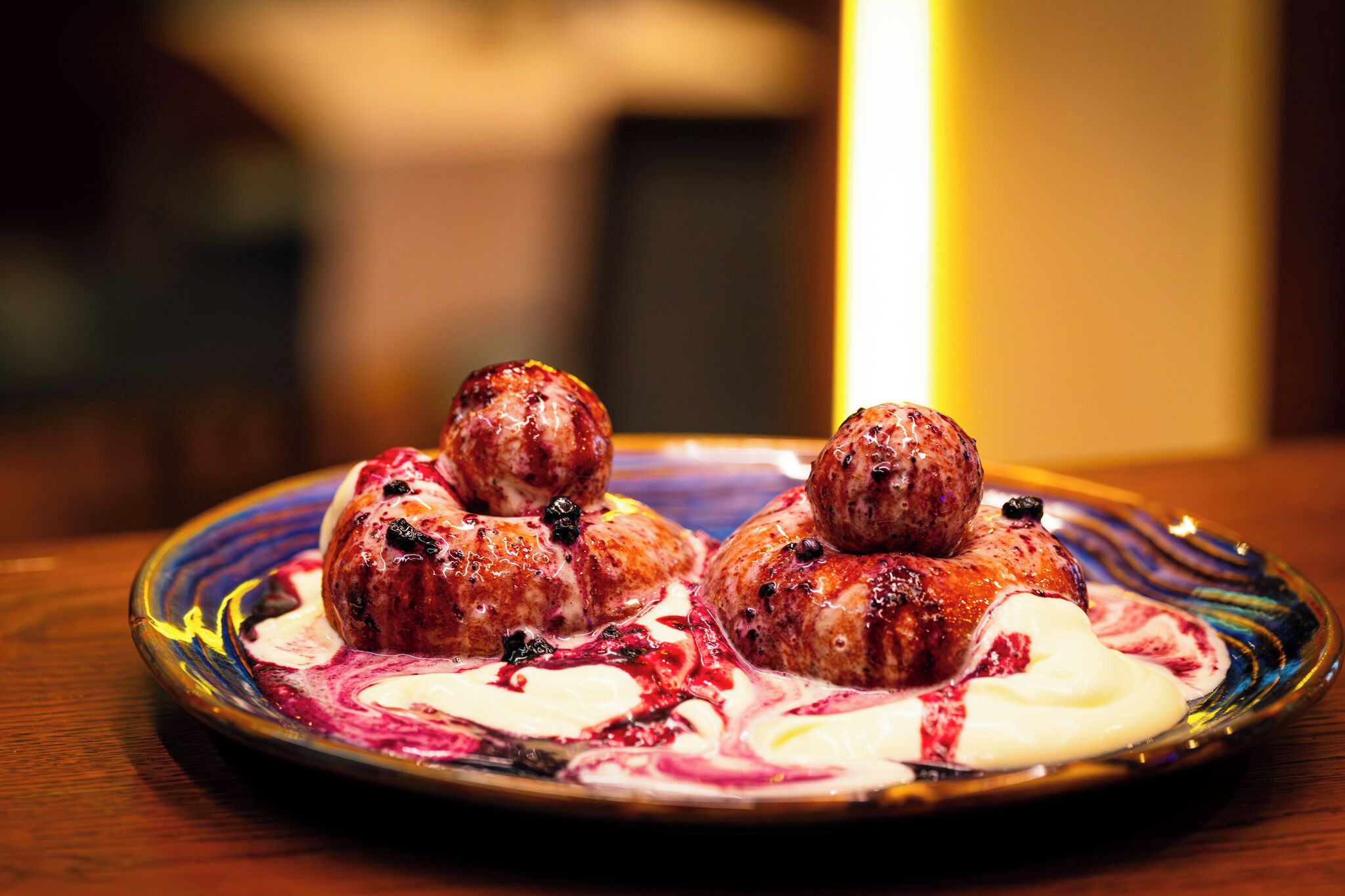 A plate with three meatballs and a swirl of cream and berry sauce.