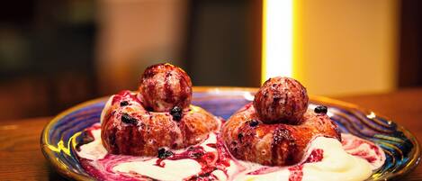 A plate with three meatballs and a swirl of cream and berry sauce.
