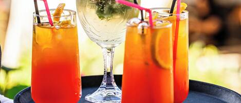 Three glasses of a red beverage on a tray, with a clear glass in the center.