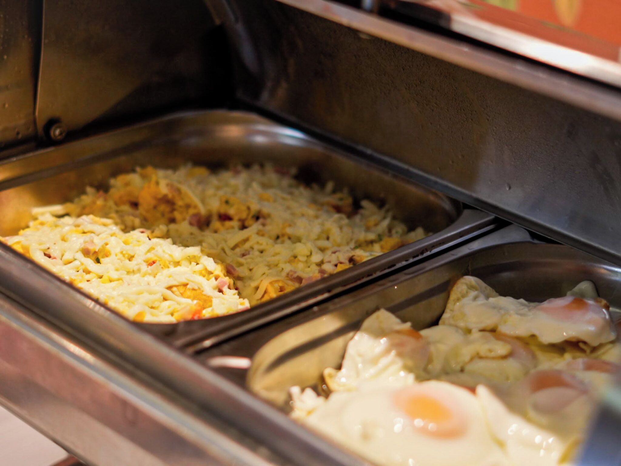 A buffet with various dishes including scrambled eggs, hash browns, and a casserole.
