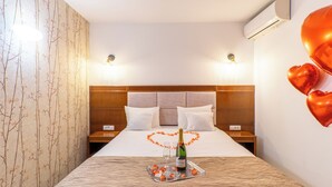 A hotel room with a bed, a nightstand, a wall-mounted air conditioner, and a decorative heart made of balloons on the wall. - Hotel Bucheland (Gura Humorului)