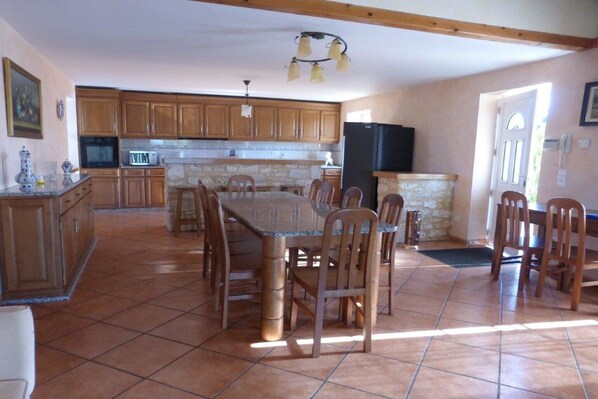 A spacious kitchen with wooden cabinets, a dining table, and chairs. - House in Monségur with Panoramic Views (Monségur)