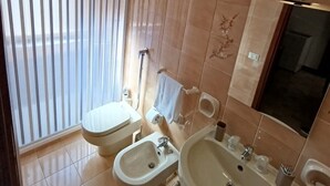 Un baño con dos inodoros, un bidé, un lavabo y un espejo.