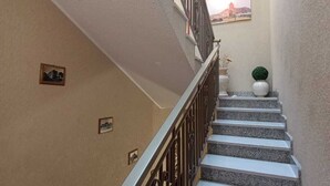 Una escalera con barandilla de metal, una planta en maceta y un cuadro en la pared.