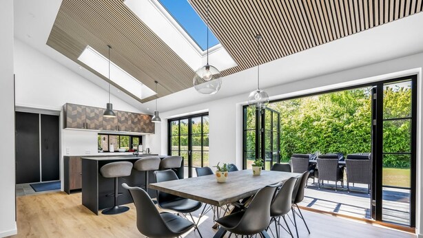 Una cocina moderna con comedor, ventanas amplias y vista a zonas verdes.