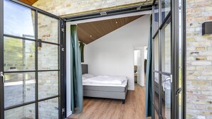 Un dormitorio moderno con cama, suelo de madera y pared de ladrillo.