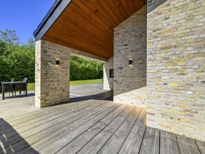 A covered outdoor area with a wooden deck, stone walls, and a table with chairs. - "Tähti" - 425m from the sea by Interhome (Føllenslev)