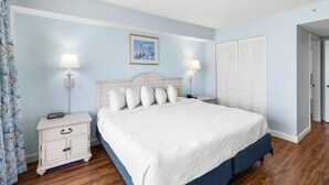 A bedroom with a bed, nightstands, a dresser, and a closet.