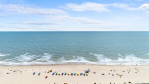 A beach with people and colorful umbrellas.