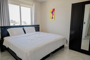 A bedroom with a bed, a wardrobe, and a window with curtains. - Spacious 4-bedroom apartment 2 km from Eagle beach - Dream Suites Aruba (Noord)