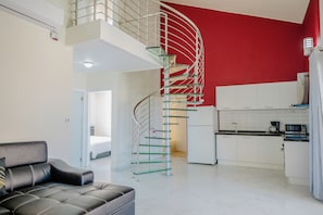 En moderne lejlighed med trappegang i spiral, et køkken og en stue med sofa.