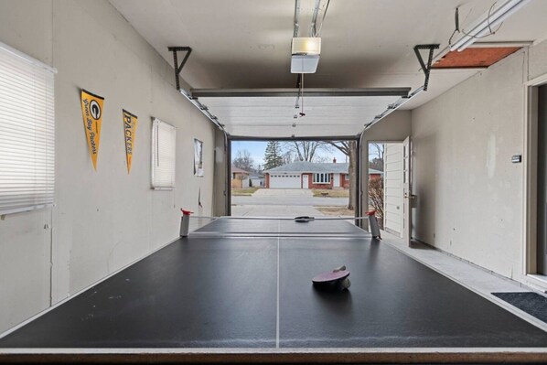 Un pasillo con cancha de tenis, proyector y puerta que da al exterior.