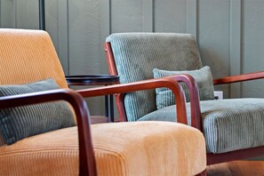 Une rangée de trois fauteuils rembourrés, dotés d’accoudoirs en bois, disposés côte à côte devant un mur lambrissé.