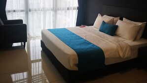 A hotel room with a large bed, a chair, a view through the window, and a painting on the wall. - Sam's Vacation @ The Straits Suite Residence formerly Ramada Suite by Wyndham (Johor Bahru)