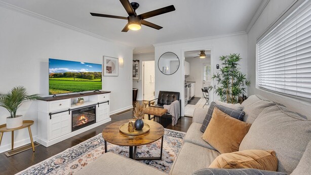 A modern living room with a fireplace, a television, and a ceiling fan. - Boho Westside Retreat | Fire Pit + Walk to Eats (Atlanta)