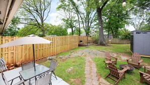 A backyard with a patio area, outdoor furniture, a wooden fence, and a grill. - Boho Westside Retreat | Fire Pit + Walk to Eats (Atlanta)