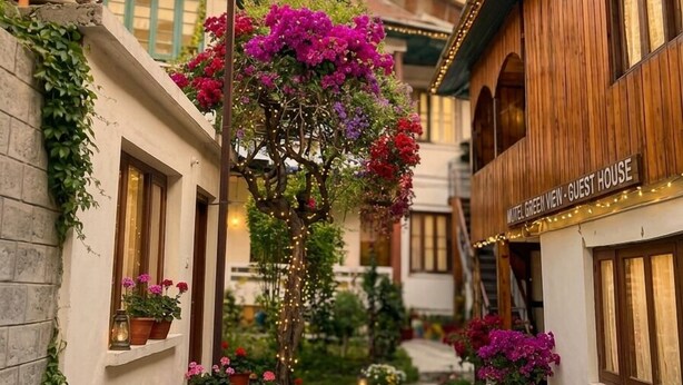 A narrow alleyway with buildings on either side, a tree with purple flowers, and a sign for 'Motel Green View - Guest House'. - Hotel New Green view-apart (Srinagar)