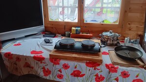 Una cocina con estufa, sartén y mesa con mantel estampado con amapolas.