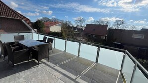 Een balkon met glazen hekwerk, met uitzicht op een woonwijk.