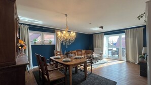 Een eetruimte met een kroonluchter, een houten tafel en stoelen.