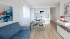 A modern apartment with a living room, a dining area, and a kitchen. - Elegant downtown hideaway (Lignano Sabbiadoro)