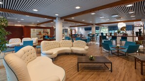 Un hall d’entrée spacieux avec un canapé incurvé, des fauteuils bleus et une table basse.