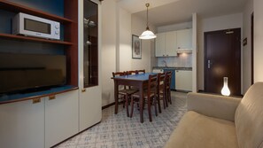 A compact living space with a dining area, kitchenette, and a sofa.