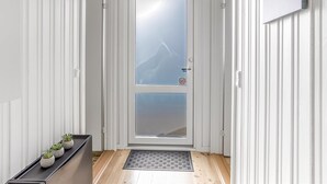 Pasillo con una puerta blanca que tiene un panel de vidrio esmerilado y vista a la montaña.