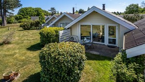 Una hilera de casas de una planta con patios adosados, rodeadas de céspedes y setos cuidados.