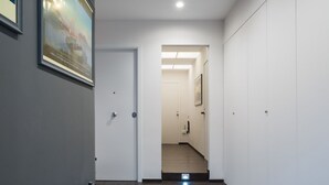 A hallway with a door leading to a staircase, a framed picture on the wall, and a white closet. - Santa Chiara in the city centre (Napoli)