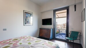 A bedroom with a bed, a dresser, a television, and a balcony with chairs. - Santa Chiara in the city centre (Napoli)